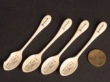 four spoons with writing on them are next to a penny