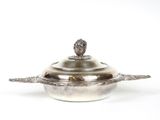 une casserole ancienne en métal argenté, munie d'un couvercle et ornée d'un motif floral sur le dessus