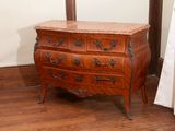 a small chest of drawers with marble top on a wooden floor