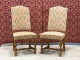 pair of upholstered chairs in front of a red wallpapered wall