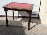 a small wooden table with a red top on the sidewalk