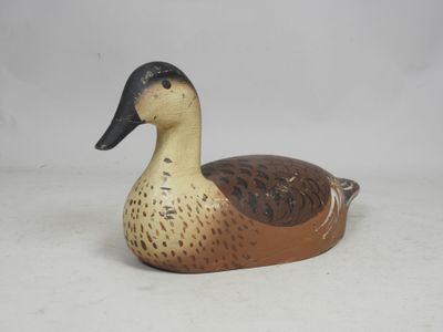 a brown and black duck sitting on a white surface
