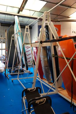 Plusieurs planches de surf sont alignées sur un support dans une pièce.