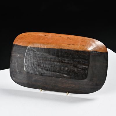 une assiette en bois posée sur une table blanche, sur fond noir