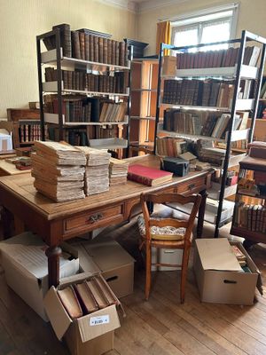 une pièce remplie de livres et de cartons posés par terre