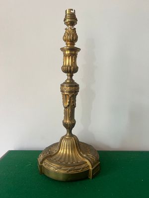 un bougeoir ancien en laiton posé sur une table verte