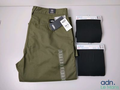 un pantalon vert pour homme et un pantalon noir posés sur une table blanche