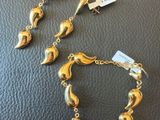 une paire de bracelets et de boucles d'oreilles dorés posés sur un fond en cuir noir