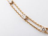 a close up of a gold chain necklace with three diamonds on it