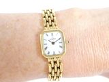 a woman ' s wrist that has a gold watch on it