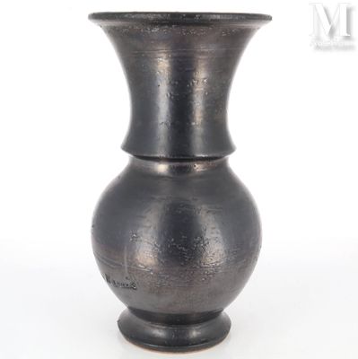 un vase noir posé sur une surface blanche