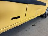 the door of a yellow car with a black stripe on the side of it