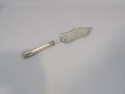 une cuillère en argent avec un manche, posée sur une surface blanche