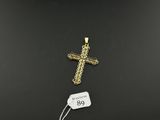 a gold cross pendant with a tag on a black background