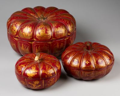 trois citrouilles rouges et dorées posées les unes à côté des autres sur une table