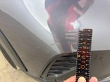 a person that is holding a ruler in front of a car