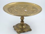 an antique brass plate on a pedestal on a white background