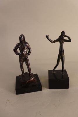 two bronze statues of a man and a woman on black bases