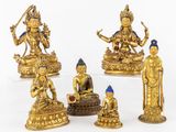 cinq figurines en or représentant des bouddhas assis sur une table