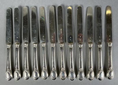 six silverplated knives and six spoons are lined up on a table