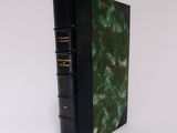 a black book with a green cover sitting on a white surface