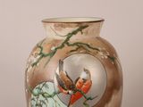 a vase with a bird painted on it sitting on a table