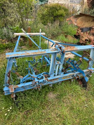 a blue plow that is sitting in the grass