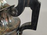 a silver teapot with a handle on a table