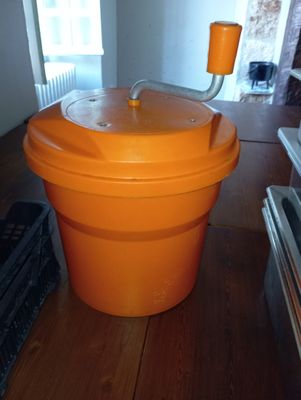 an orange plastic bucket with a lid on a wooden floor