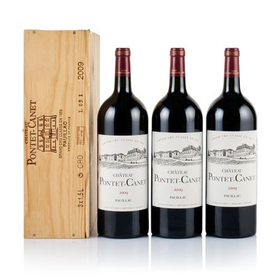 three bottles of red wine and a wooden box on a white surface