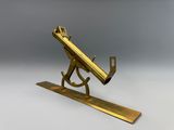 un télescope ancien en laiton posé sur un trépied, sur fond gris