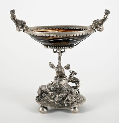 un plat ancien en argent orné d'un oiseau, posé sur un socle