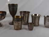 many silver cups and cups sitting on a white table