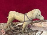 statue of a dog on a rock with a harness around it ' s neck