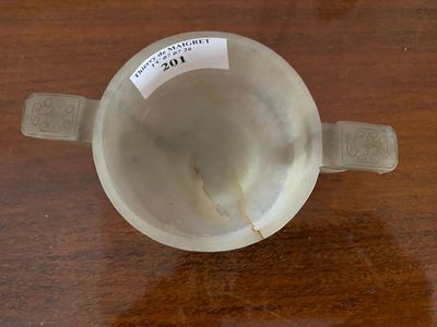 a white cup on a wooden table with a label on it