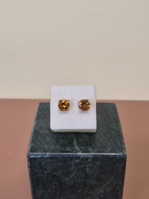 une paire de boucles d'oreilles dorées posées sur un bloc de marbre