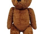 a brown teddy bear that is sitting on a white surface