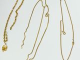 three gold necklaces and a gold ball on a white background