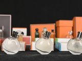 several bottles of perfume sitting on top of a table next to orange boxes