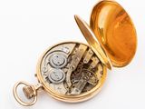 a gold pocket watch sitting on a white surface