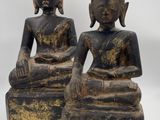 two statues of buddhas sitting on blocks on a white background