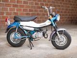 a blue and white motorcycle parked in front of a brick wall