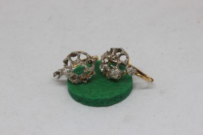 pair of gold and diamond skull earrings on a green base