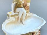 une figurine représentant une femme assise sur un coquillage