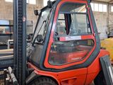 a forklift in a warehouse with a yellow truck in the background