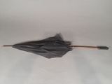 a black umbrella with a wooden handle laying on a white surface