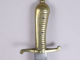 a gold colored sword with a black handle on a white wall