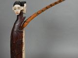 wooden figurine of a woman holding a bamboo stick and wearing a hat