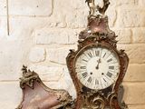 une horloge posée sur une table, à côté d'une paire de chaussures