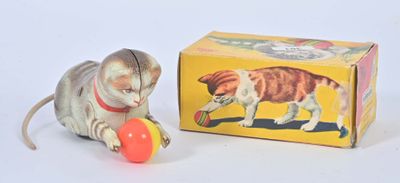 un petit chat en peluche qui joue avec une balle devant une boîte